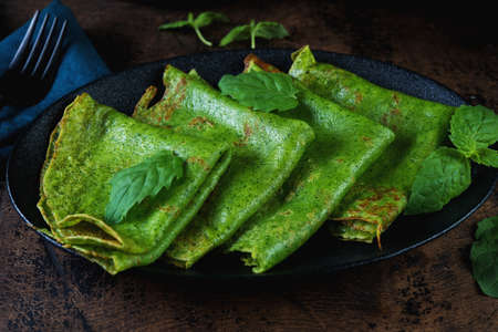 Close up Spinach thin pancakes are green on a wooden table. Horizontal photo.の写真素材