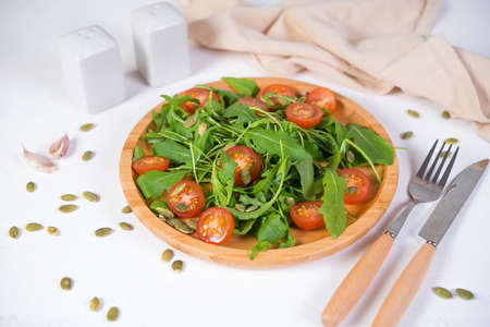 Fresh vegetable salad. Vegetarian salad of arugula, cherry tomatoes and pumpkin seeds in a wooden...