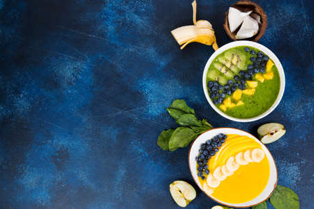 Two cups of different smoothie bowl of green and yellow fruits. The concept of healthy eating. Horizontal photo with copy space. Top view.の写真素材