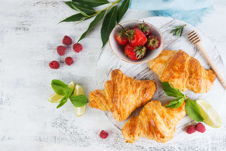Still life of fresh morning croissants and berry tea in a glass teapot on a white wooden background. Horizontal photo of Breakfast.の写真素材