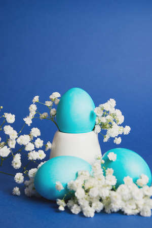 Painted Easter eggs on a trendy blue background. Vertical photo with selective focus.の写真素材