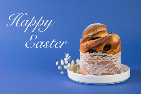Easter holiday cake with raisins lies in a plate on a trendy blue background. Horizontal close-up...