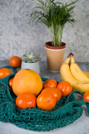 Eco-friendly shopping bag for fruit from the store, lying on a gray table surrounded by home flowers .Selective focus, vertical photo.の写真素材