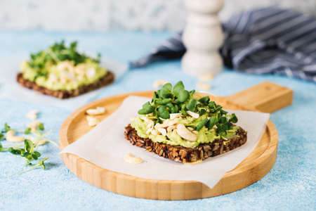 Vegan green toast with avocado, nuts and microgreens, selective.
