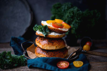 Homemade bagels with cheese and vegetables for brunch on an old wooden backgroundの写真素材