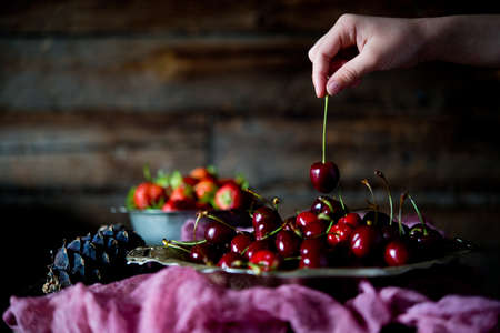 Red ripe cherries in a cup on a rustic background