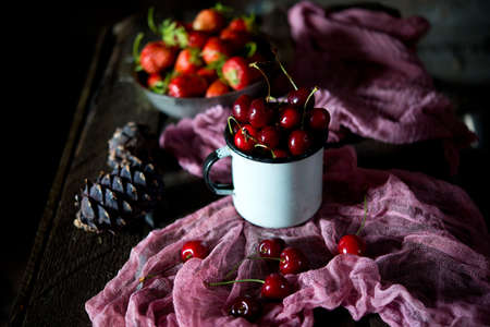 Red ripe cherries in a cup on a rustic backgroundの写真素材