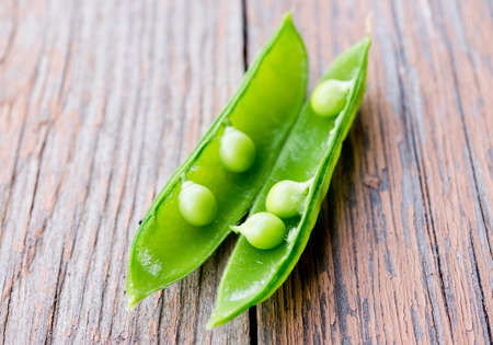 Pods of fresh garden peas on a wooden tableの写真素材