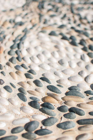 The texture of the stone wall, the road of small round and oval stones with abstract lines is lined with patternsの写真素材