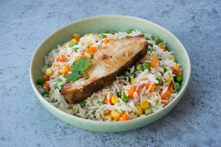 Rice with vegetables and fish steak in a plate, selective focusの写真素材