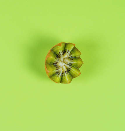 Half of a green ripe kiwi on a green background, top viewの写真素材
