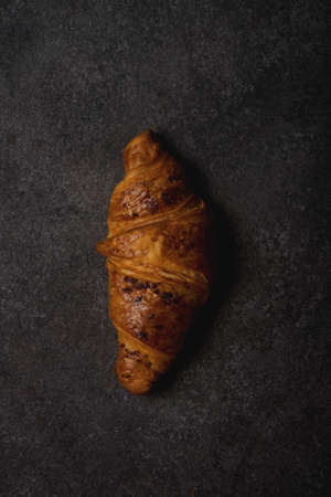 Classic French croissant with chocolate on a dark concrete backgroundの写真素材