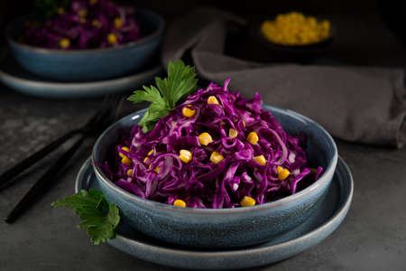 Fresh vegetarian salad with red cabbage and corn on a dark background, close upの写真素材