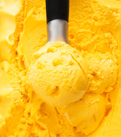 A ball of natural mango ice cream in a box. Tropical orange ice cream background