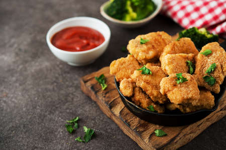 Homemade chicken nuggets with vegetables on a wooden board, copy space, selective focusの写真素材