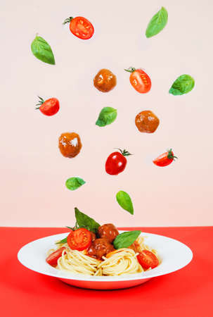 Spaghetti bolognese with meat meatballs, tomatoes and basil, flying ingredients, creative photoの写真素材