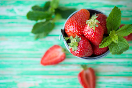 Fresh garden strawberries in a bucket on a rustic background, selective focus, top viewの写真素材