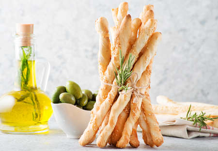 Italian bread sticks with sesame seeds and herbs on a light background, selective focus, horizontal...