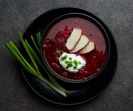 Traditional Ukrainian cuisine - borscht with sour cream and green onions, top view