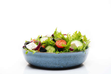 Greek salad with feta, olives, tomatoes and cucumbers isolated on a white backgroundの写真素材