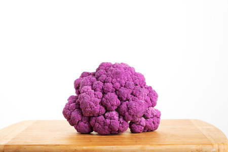 Purple cauliflower on a wooden board isolated on a white backgroundの写真素材