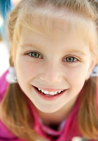 cute little girl smiling in a park close-upの写真素材