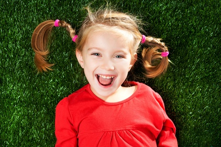 little girl smiling on a green lawn