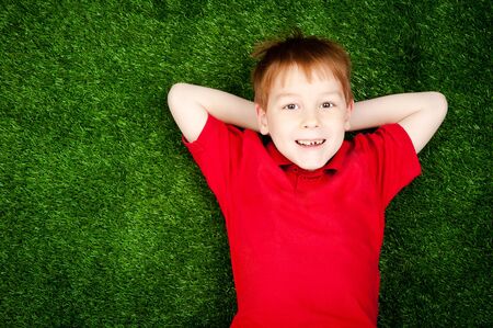 cute little boy lying on a green lawn