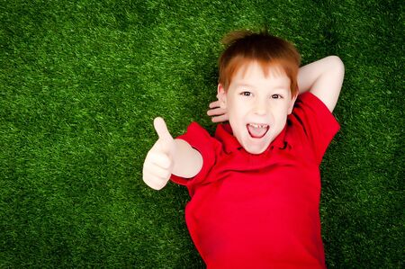 cute little boy lying on a green lawnの写真素材