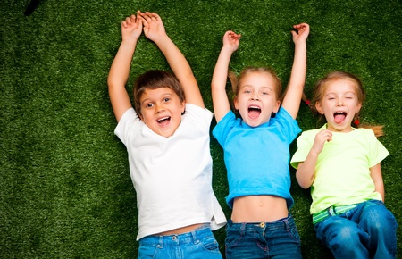 small kids lie on the green grassの写真素材