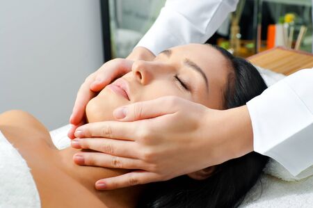 Beautiful young woman receiving facial massage with closed eyes  in a spa centerの写真素材