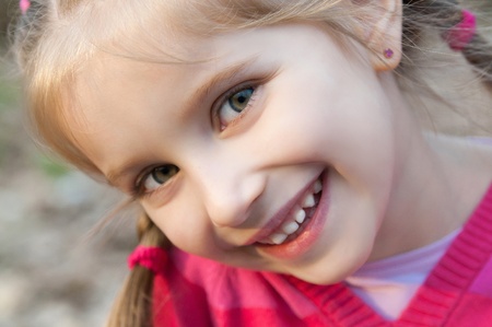cute little girl smiling in a park close-upの写真素材