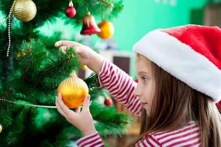 Beautiful little girl in Santa hat with Christmas decorationの写真素材