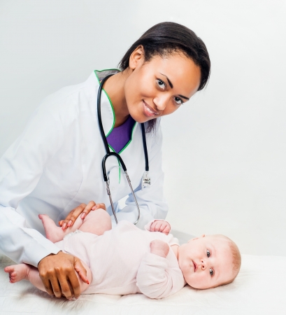 Doctor with stethoscope and small baby isolated on a light backgroundの写真素材