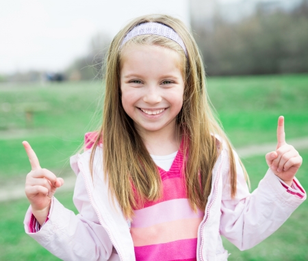 Close-up portrait of a pretty liitle girl with fingers upの写真素材