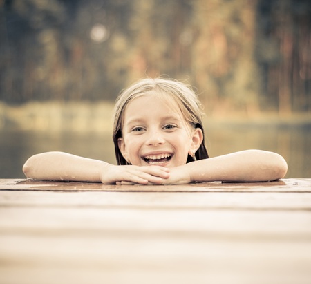 smiling little girl on the bridge in riverの写真素材
