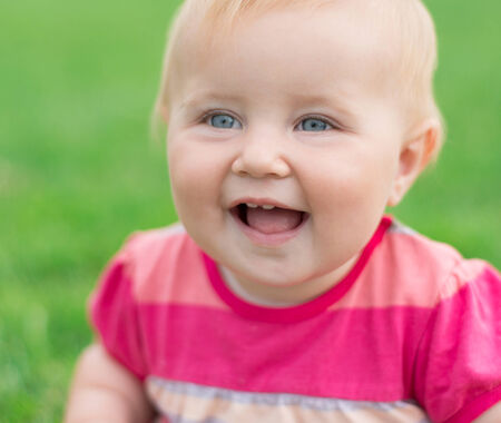 portrait of a smiling baby on a green lawnの写真素材