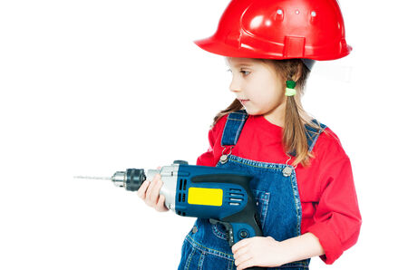Smiling Little girl in a red helmet with drill isolated on a over whiteの写真素材