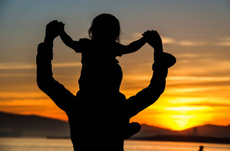 Silhouette of mother which her child against a sunsetの写真素材