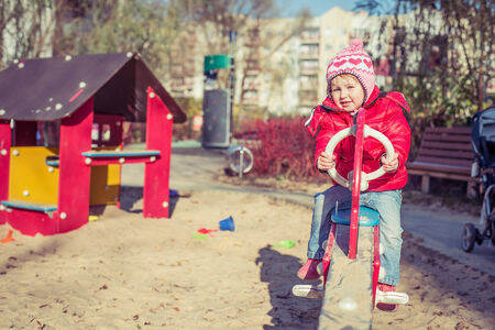 little cute girl playing at the playground in autumnの写真素材