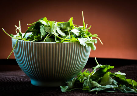 rucola in bowl on brown backgroundの写真素材