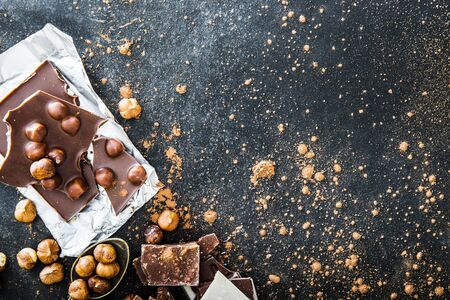 Chocolate in a foil and nuts on black table