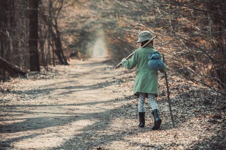 little girl goes on a footpath in the forest photo in retro styleの写真素材