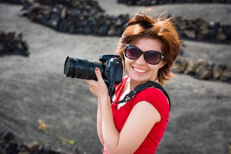 beautiful young woman in evening red dress and sunglasses with pfoto camera outdoors