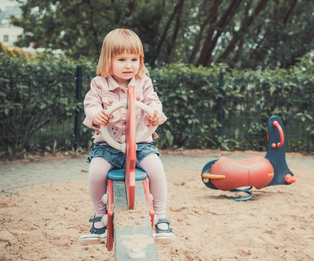 little girl on a swing on a playgroundの写真素材