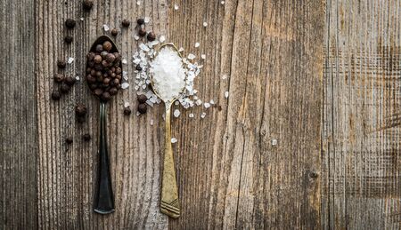 salt and pepper peas in silver spoons on wooden background