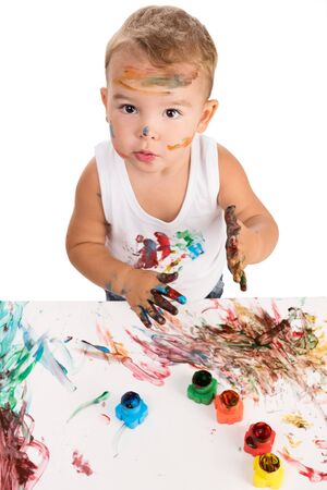 funny little boy painting with hands paper and himself on a white backgroundの写真素材