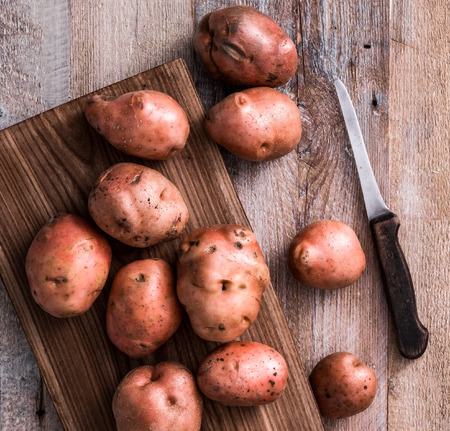 row popato on a cutting board with knifeの写真素材
