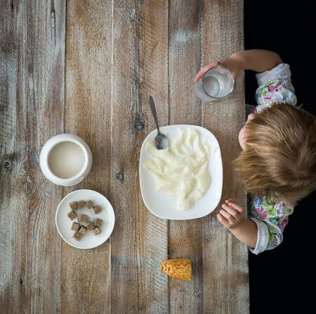 child near table having a meal with semolinaの写真素材