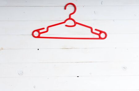 red plastic clothes hanger on white wooden backgroundの写真素材